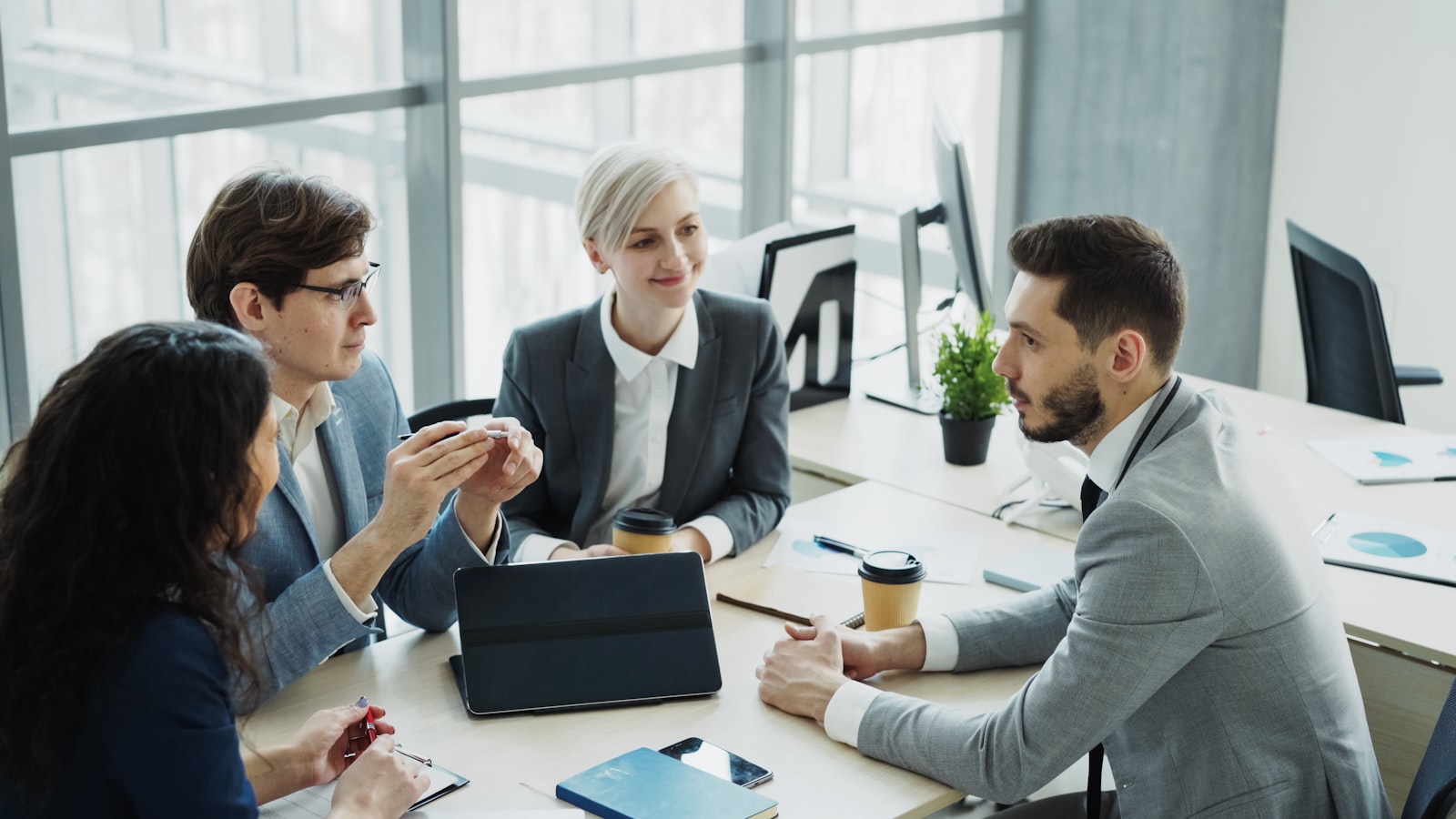 A diverse business team collaborating around a laptop in a modern office